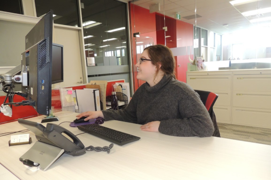 A student employee works at a computer in Student Services